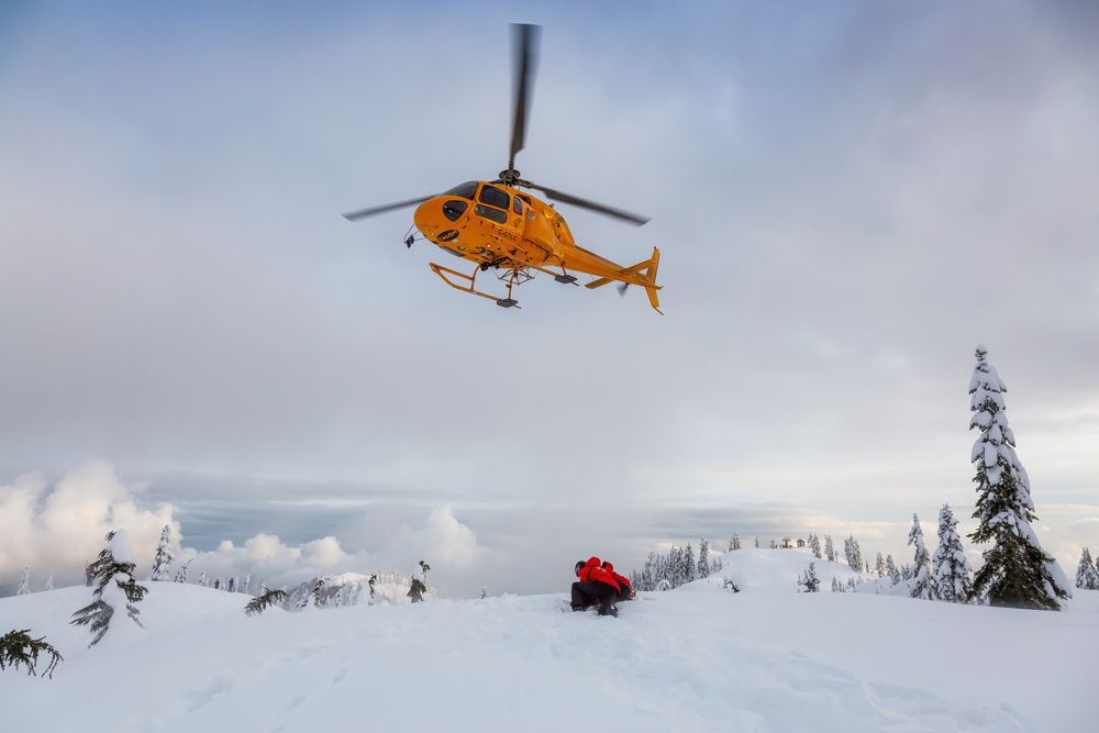North Vancouver, British Columbia, Canada - Feb 17, 2020: North Shore Search and Rescue are rescuing a man skier with a broken leg in the backcountry of Seymour Mountain with a helicopter in winter.