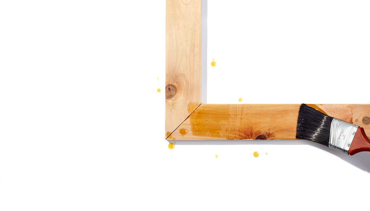 wooden window frame being painted with linseed oil on white background