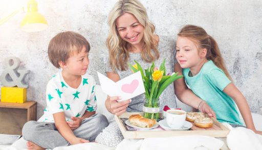 Mom and children with breakfast in bed