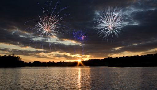 Fireworks over a lake at sunset