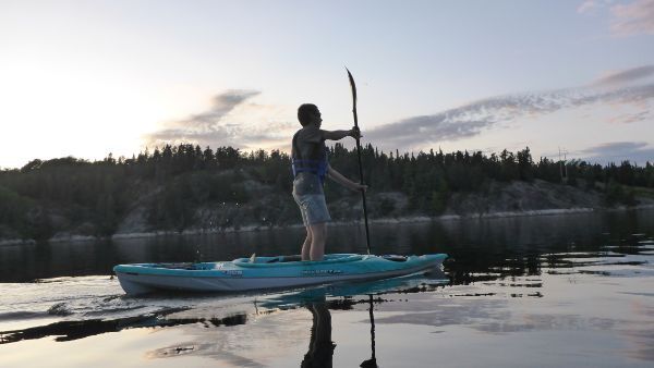 Man using a kayak like a standup paddleboard