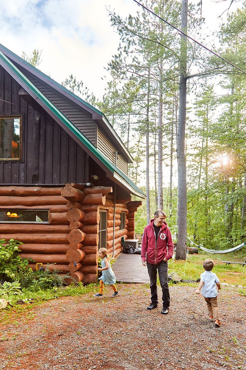 Stephen Gardner outside his log cabin with kids running around