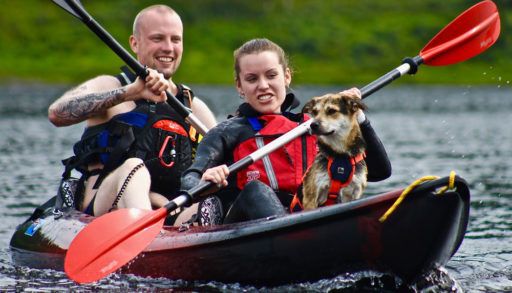 Young couple in a kayak, paddling with a dog