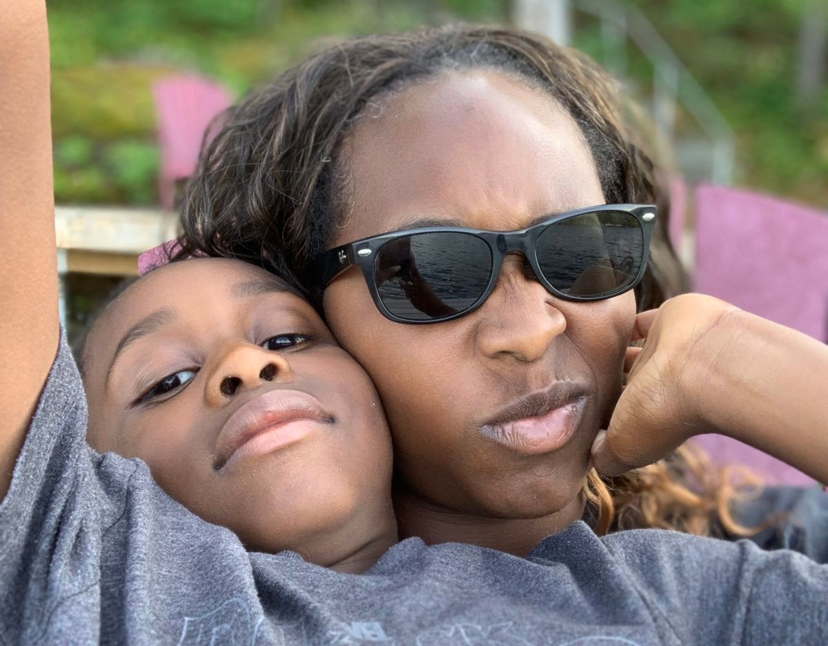 tanya hayles and her son sitting on a dock at a cottage