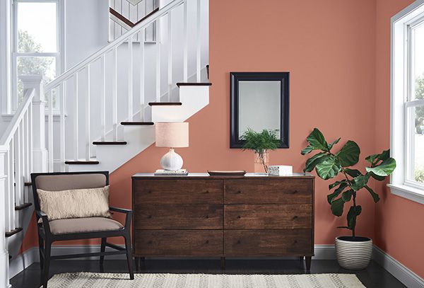 ginger red paint colour on a wall behind a deep mahogany cabinet and a white staircase