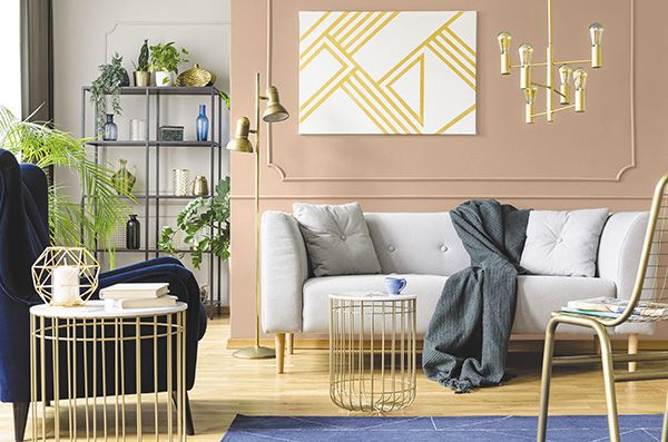 mid-tone sandy brown paint colour on a living room wall behind a while couch with gold accents