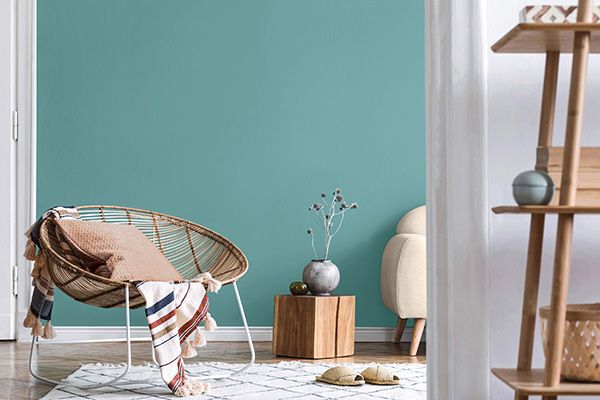 blue aqua paint colour on the wall behind a rattan round chair