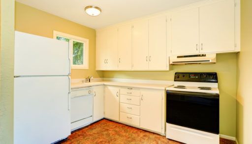 Old style simple kitchen interior with cabinets and white appliances. old stove