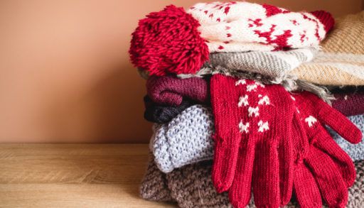 Pile of winter clothes, warm knitted clothing, hat gloves sweaters for cold weather