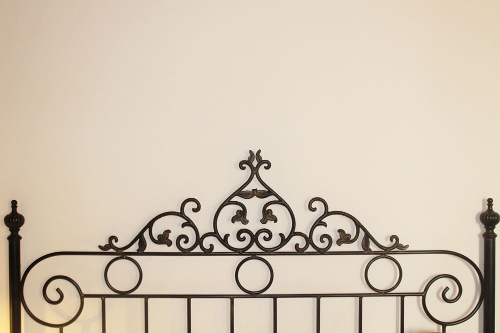 Head piece of an antique brass bed in front of a white wall