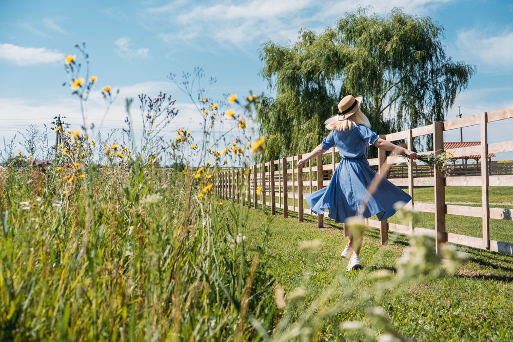 Cottagecore Farmcore Countrycore aesthetics, fresh air, countryside, slow life, pastoral life, outdoor picnics, wearing grandma clothes. Young girl in straw hat with flowers walks on country farm