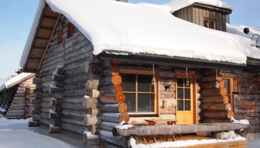 A snow-covered cabin against a blue sky background