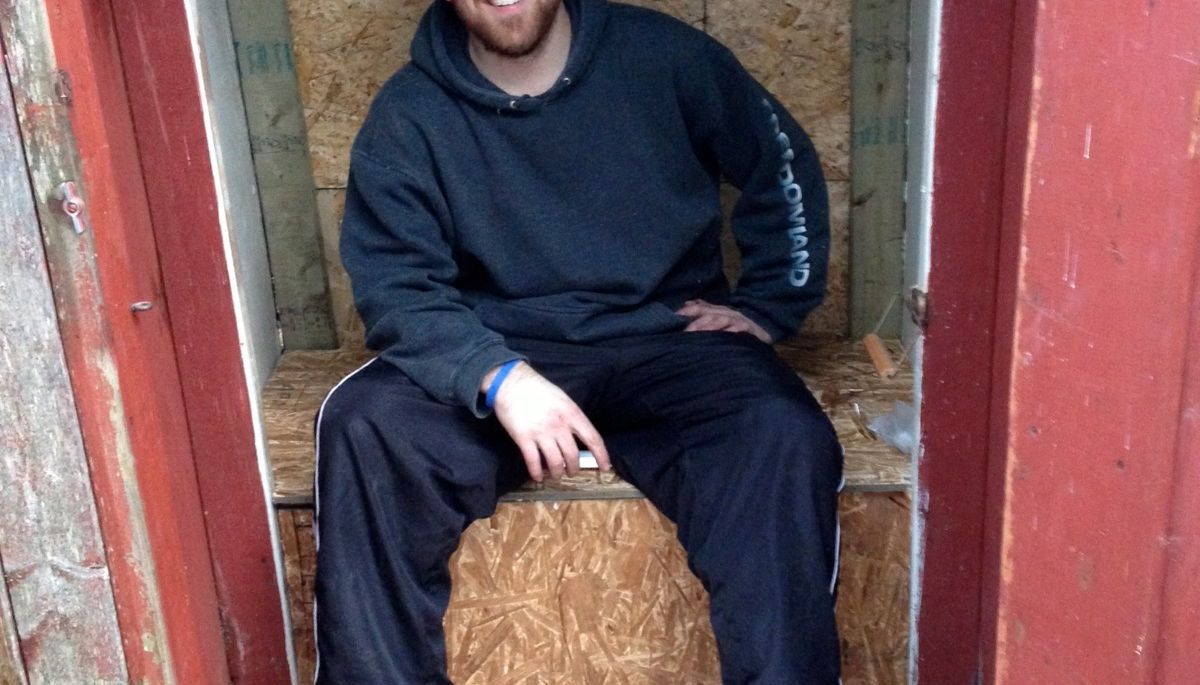 cottage coach adam holman sitting in his rebuilt outhouse
