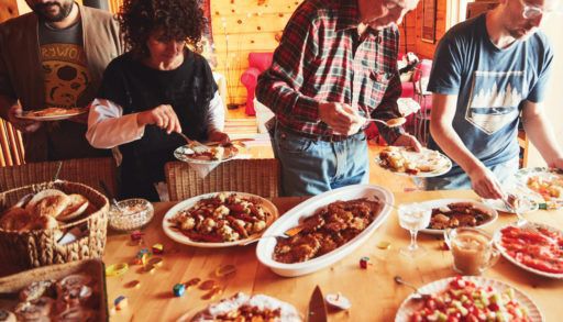 family members crowding around a buffet style Hanukkah brunch featuring latkes