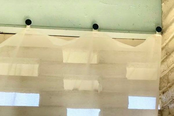 wide shot of drawer knobs being used to hang white curtains, upcycle