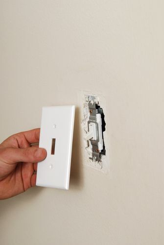 An electrician removing a light switch plate