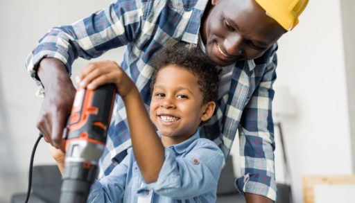 adorable african-american father and son using drill