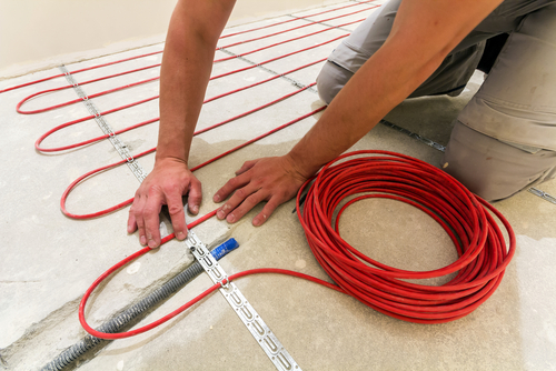 Worker installing heating cable for warm floor.