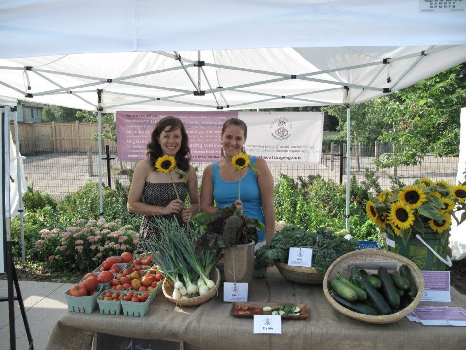 Two women holding sunflowers at an Elmgrove Organic Collective vendor
