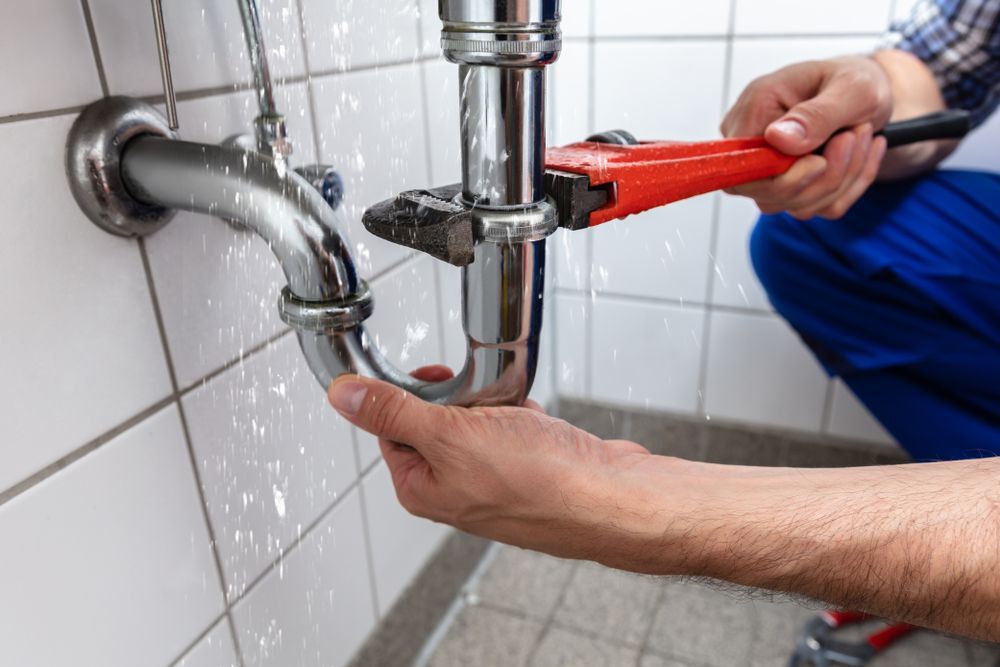 A closeup of the hands of a man fixing a plumbing pipe