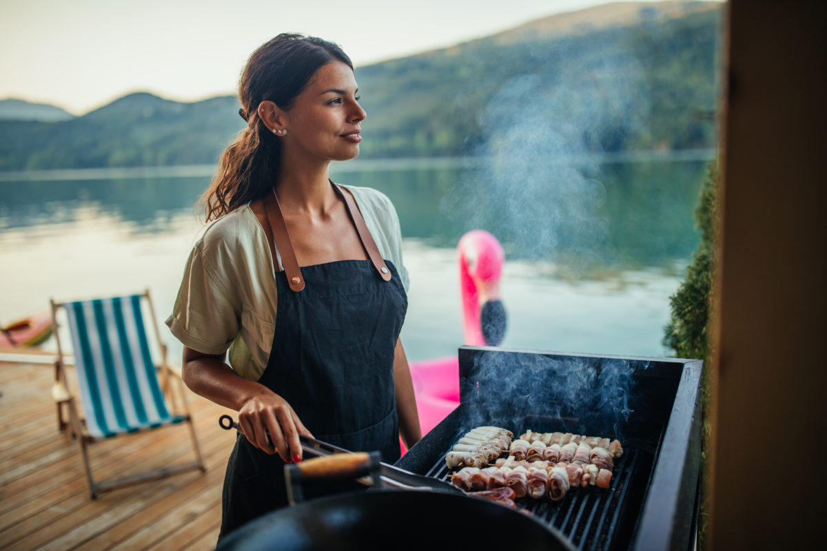 women cooks on grill at cottage with barbecue toolkit