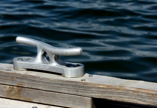 Dock cleat on a wooden dock next to a lake