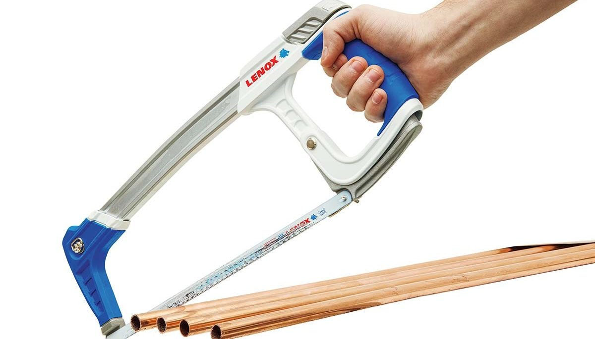 hand holding a high-tension hacksaw cutting copper pipe on white