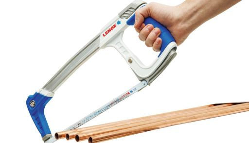 hand holding a high-tension hacksaw cutting copper pipe on white