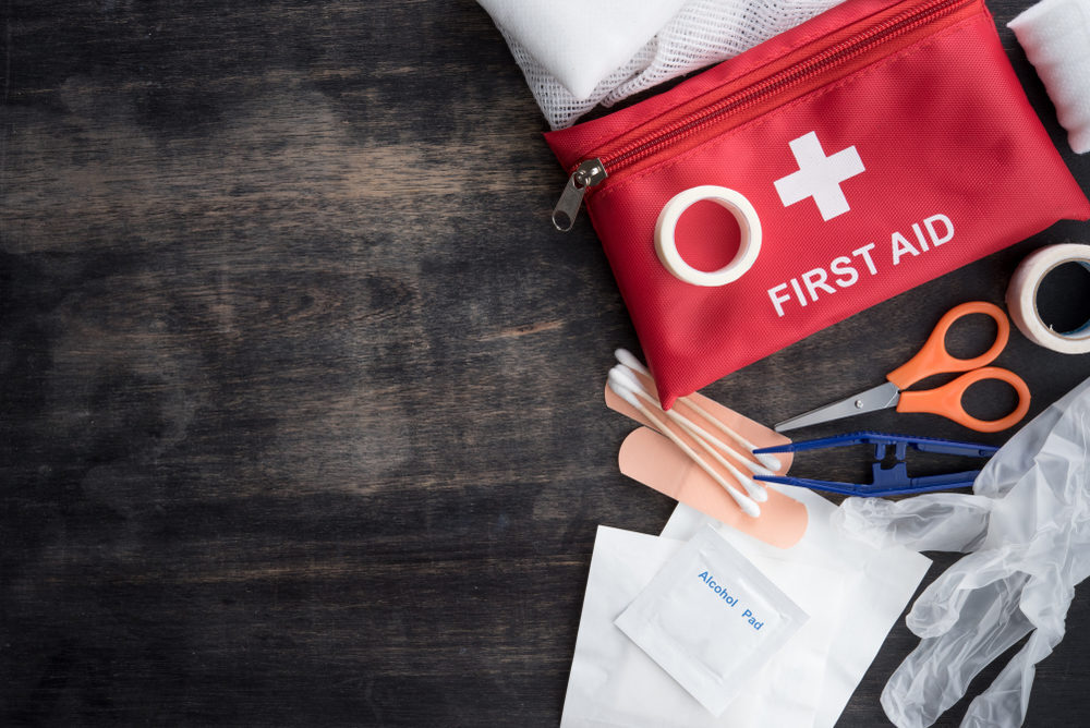 A first aid kit containing bandaids, cotton swabs, scissors, an alcohol pad and gloves.