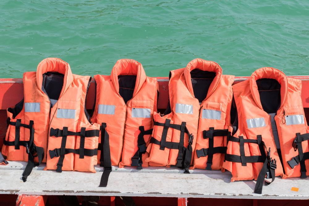 Close-up of orange life jackets on a boat with a background of water.