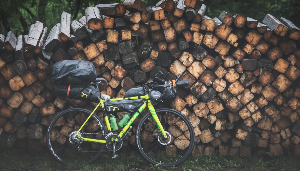 bikepacking bike by woodpile