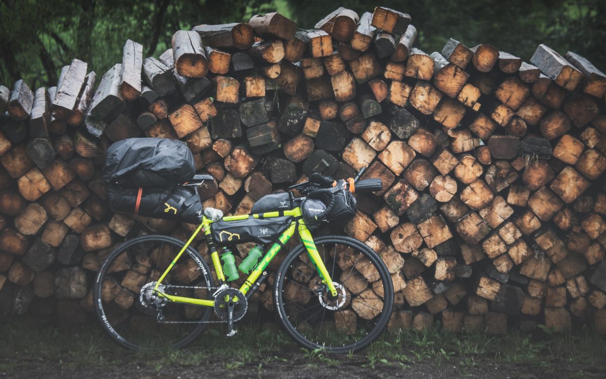bikepacking bike by woodpile