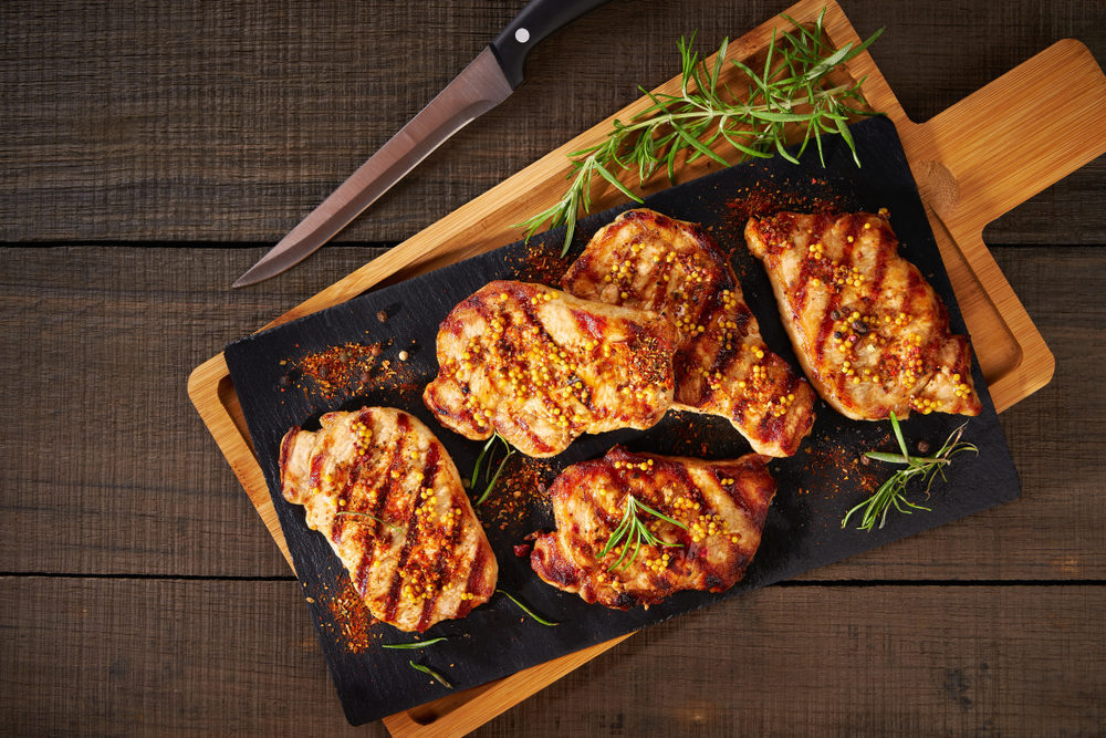 A tray of grilled pork chops on a picnic table
