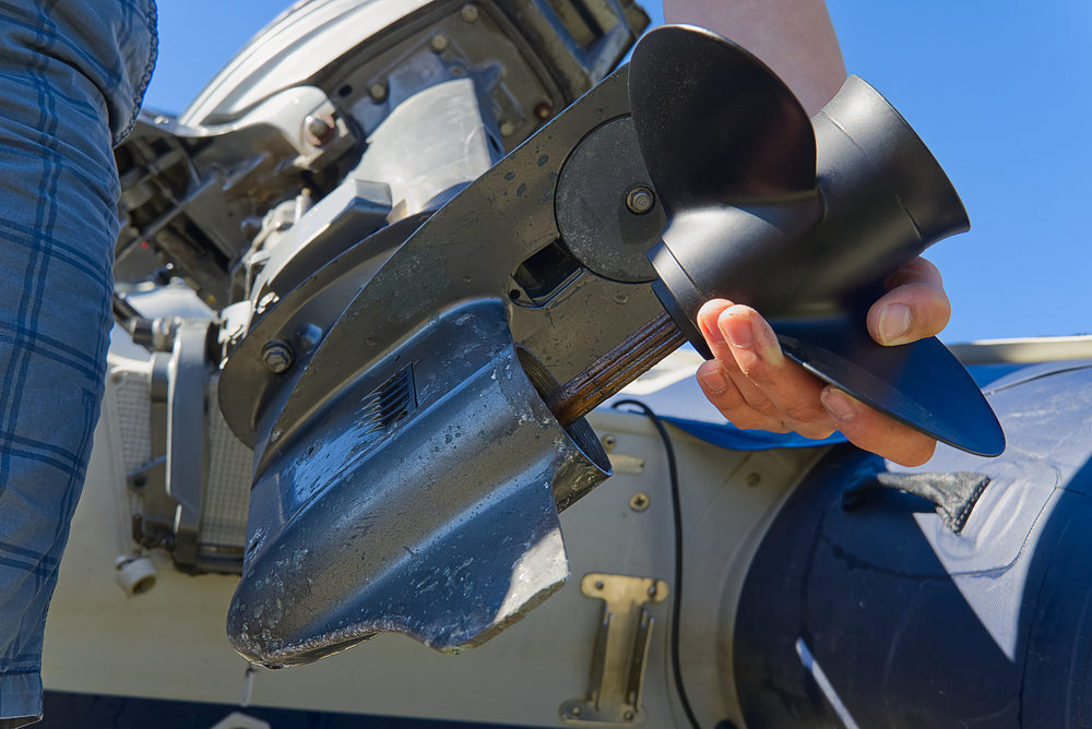 Close up of man changing an outboard engine