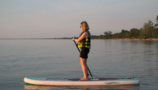 A lady stand up paddleboarding on the water.