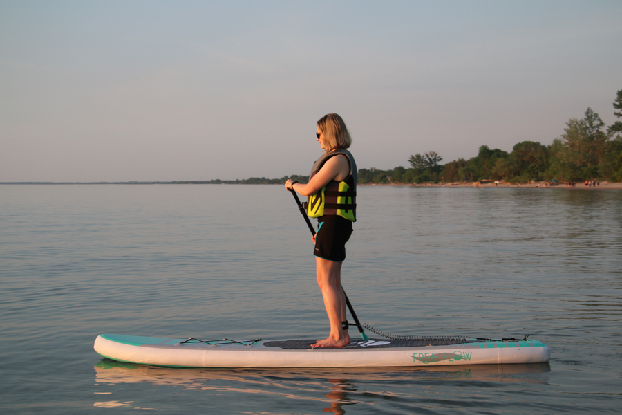 A lady stand up paddleboarding on the water.