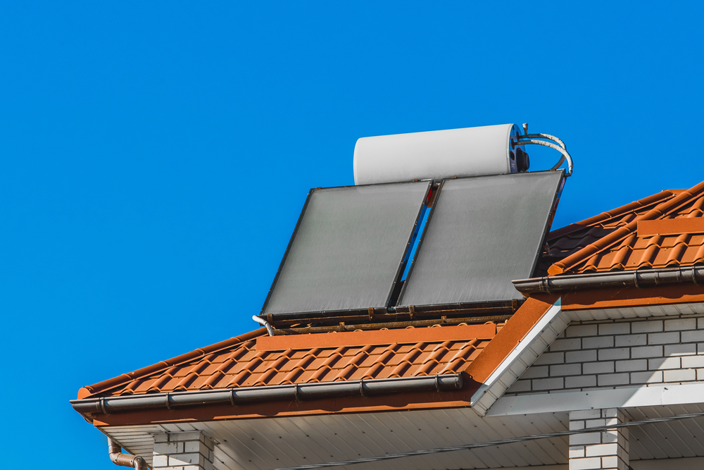 A solar water heater on the roof of a hotel against the background of a blue sky.