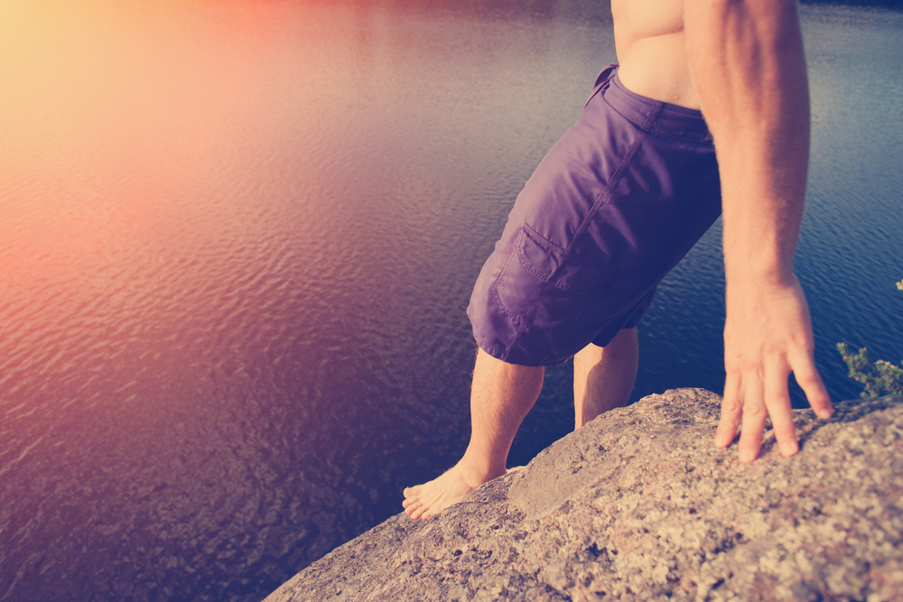Man preparing to cliff jump into the lake