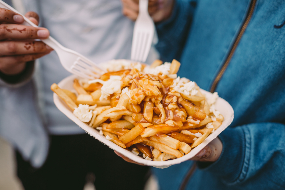 Two people eating poutine