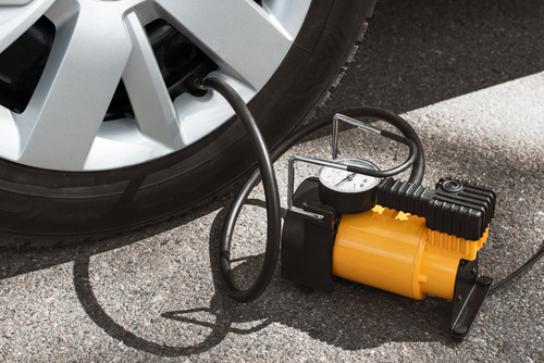 Automobile compressor. Electric pump inflates a car wheel close-up, emergencies