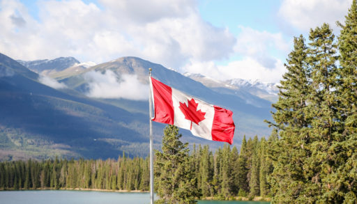 A Canadian flag flying in front of a lakeside background