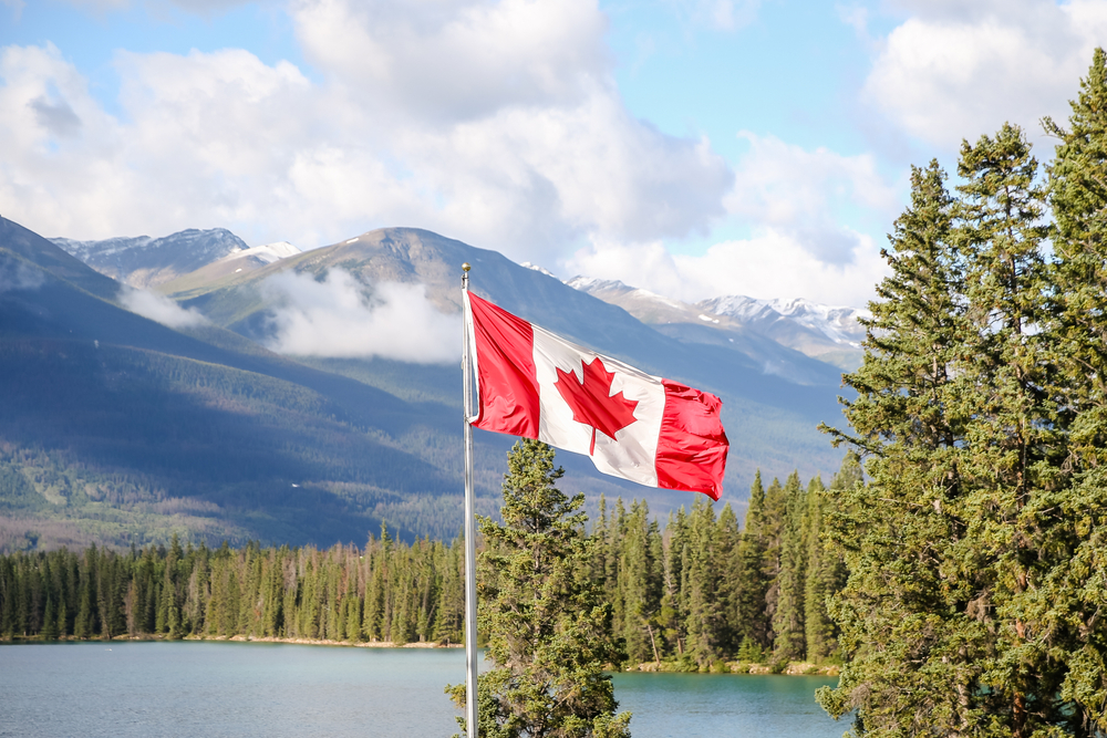 A Canadian flag flying in front of a lakeside background