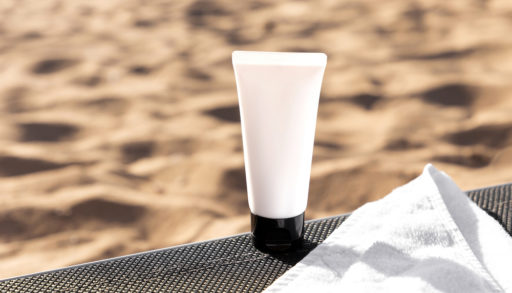 A bottle of sunscreen against a sandy background