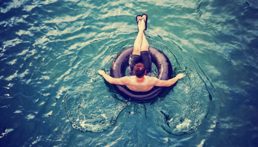 A man floating in the lake on a black inflatable tube