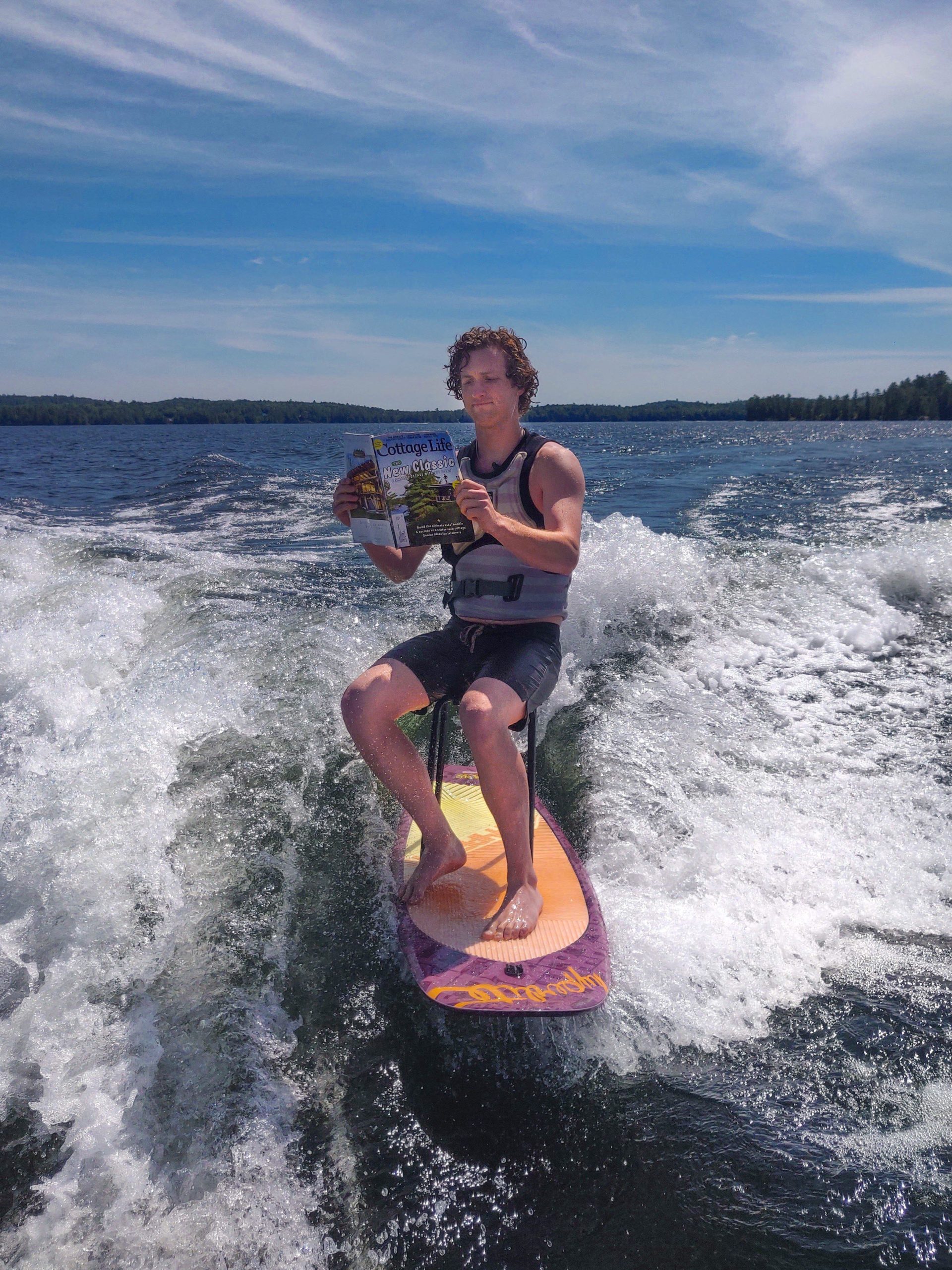 Boy surfing while reading a magazine on water