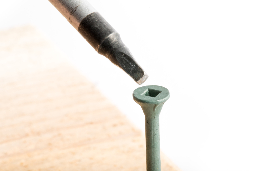 Close-up shot of Robertson style screwdriver and a wood screw against a white backdrop, fastener