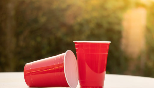 Plastic red solo drinking cups for beer pong or drinking games with green background on a white table, measure