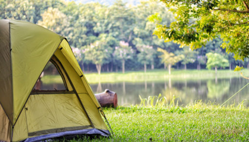 Green camping tent near lake