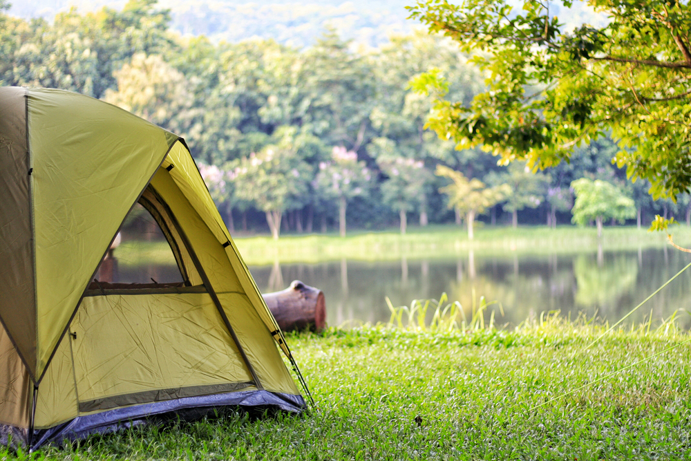 Green camping tent near lake