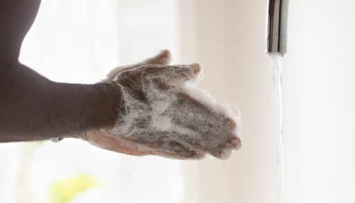 A close-up of black male hands covered in soap bubbles
